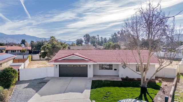 view of front facade with stucco siding, a mountain view, a garage, driveway, and a tiled roof