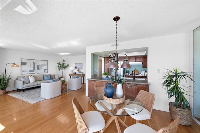 dining space with light wood-style flooring and a textured ceiling