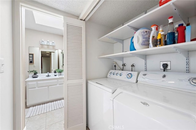 laundry area with light tile patterned floors, a textured ceiling, a sink, and washing machine and clothes dryer