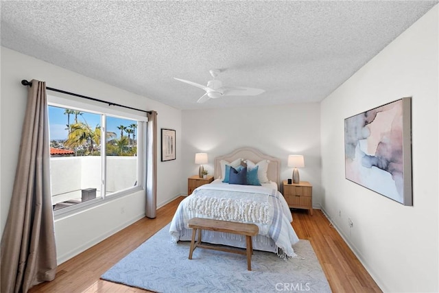 bedroom with a textured ceiling, light wood-style flooring, and a ceiling fan