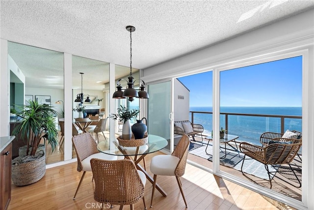 dining space featuring a textured ceiling, a water view, wood finished floors, and a notable chandelier