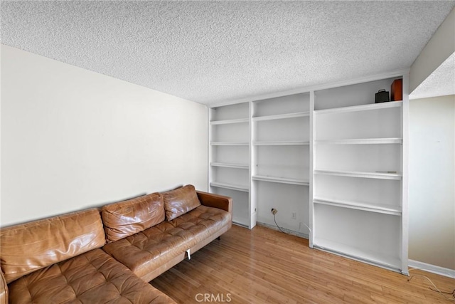 living area featuring a textured ceiling, wood finished floors, and built in features