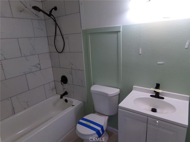 bathroom with bathtub / shower combination, a textured wall, vanity, and toilet