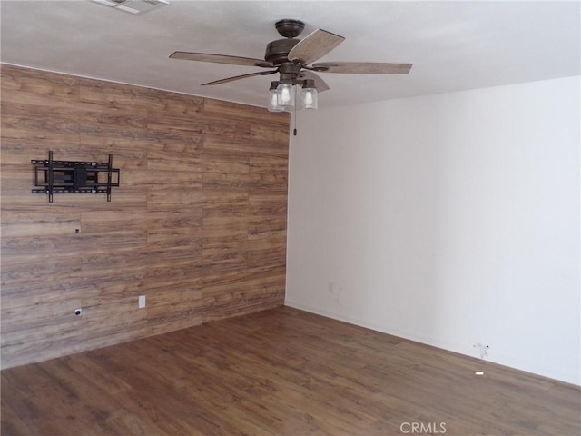 unfurnished room featuring ceiling fan, wooden walls, and wood finished floors