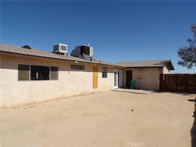 back of house with fence, cooling unit, and stucco siding