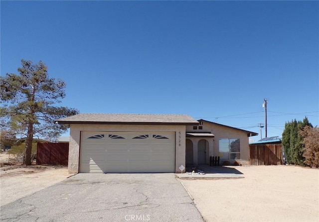 view of front facade featuring driveway, fence, an attached garage, and stucco siding