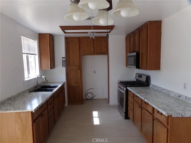 kitchen with brown cabinetry, pendant lighting, stainless steel appliances, and a sink