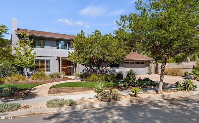 view of front of property with a garage, concrete driveway, fence, and stucco siding