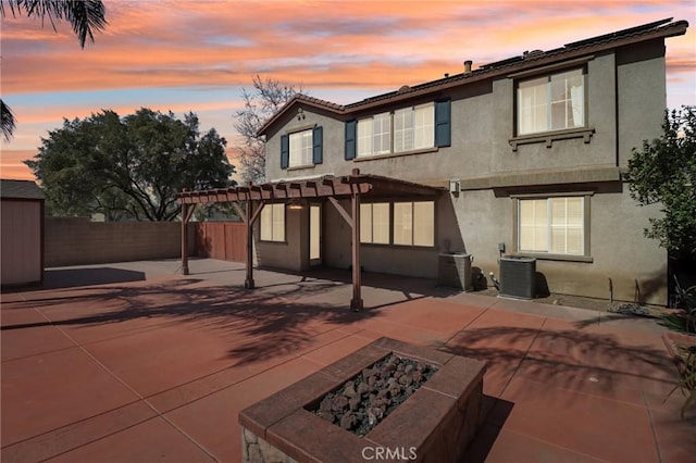 back of property at dusk with a patio, an outdoor fire pit, central AC unit, and stucco siding