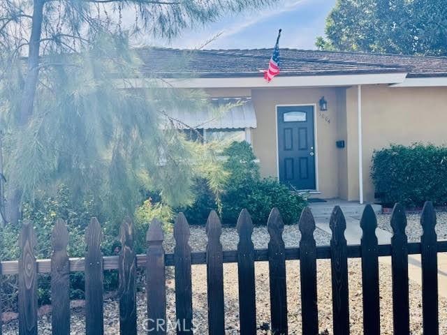 doorway to property featuring fence and stucco siding