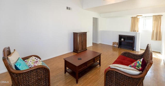 living area with wood finished floors, visible vents, and baseboards