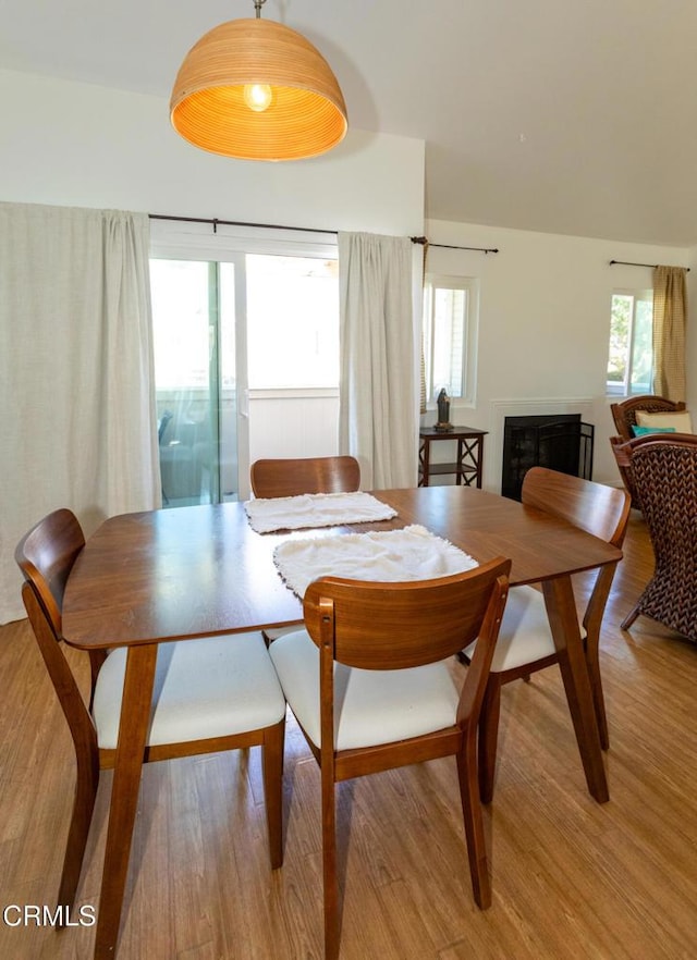 dining room featuring light wood-style floors, plenty of natural light, and a fireplace