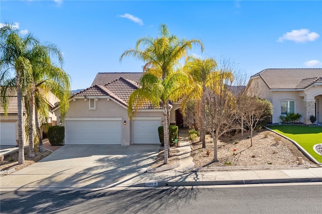 view of front of property with concrete driveway, a tiled roof, an attached garage, and stucco siding