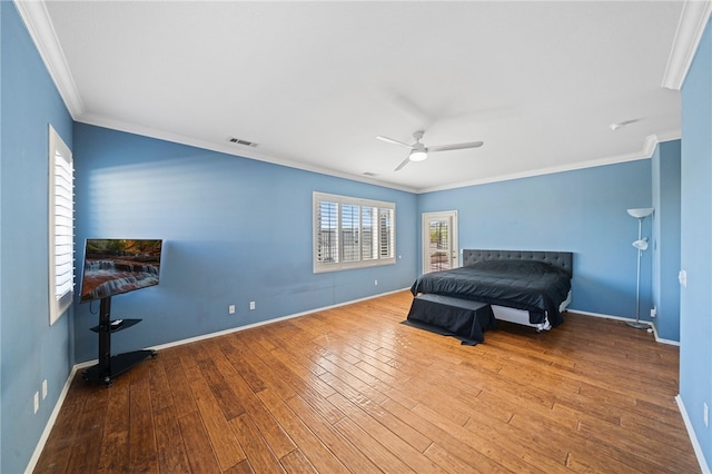 bedroom featuring baseboards, wood finished floors, and crown molding