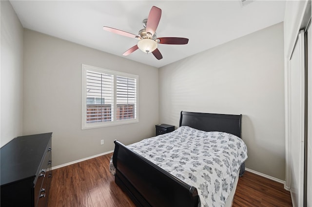 bedroom with a ceiling fan, baseboards, dark wood finished floors, and a closet