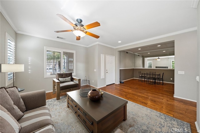 living room featuring ornamental molding, visible vents, light wood-style flooring, and baseboards