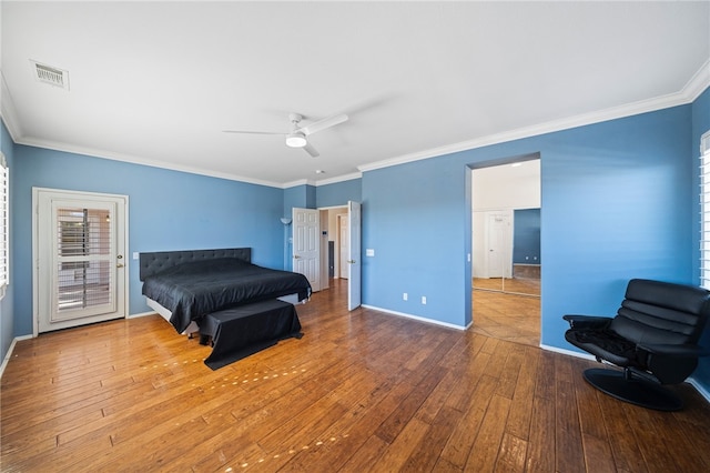 bedroom with baseboards, wood finished floors, visible vents, and crown molding