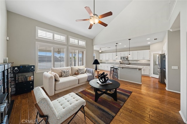 living area with high vaulted ceiling, recessed lighting, dark wood-style flooring, a ceiling fan, and baseboards