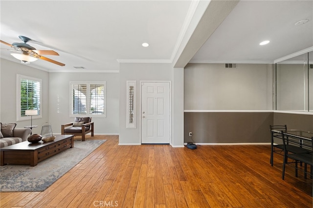 entrance foyer with baseboards, visible vents, a ceiling fan, ornamental molding, and wood finished floors