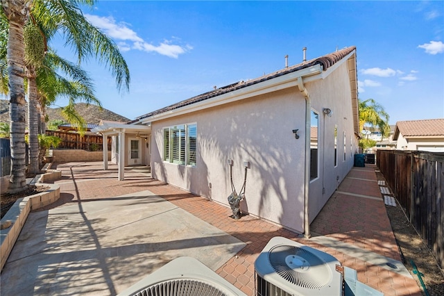 rear view of property with a fenced backyard, a patio, cooling unit, and stucco siding