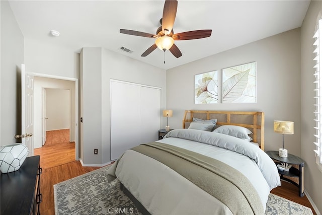 bedroom featuring baseboards, visible vents, ceiling fan, wood finished floors, and a closet