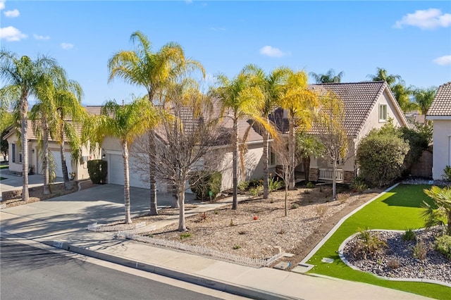 obstructed view of property featuring a garage, a tile roof, driveway, and stucco siding