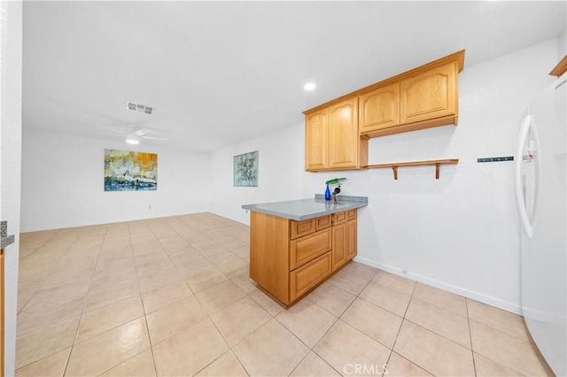 kitchen with light tile patterned flooring, a peninsula, visible vents, a ceiling fan, and freestanding refrigerator