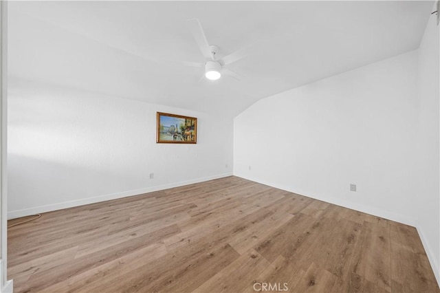 spare room with a ceiling fan, lofted ceiling, baseboards, and wood finished floors