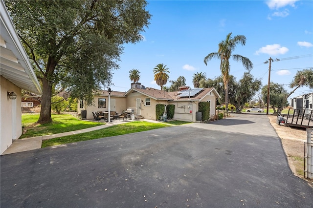 view of front of home with a front lawn and solar panels