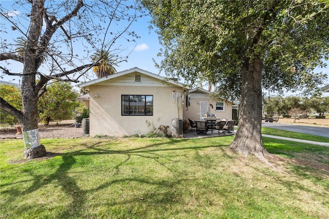 view of front of house with a front lawn, a patio area, and stucco siding