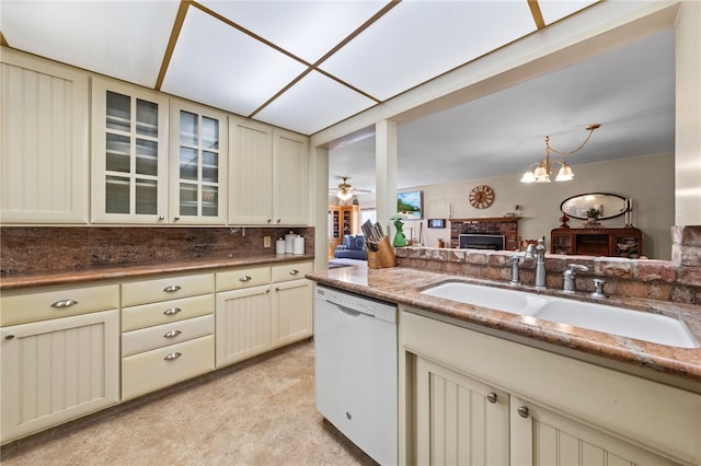 kitchen featuring cream cabinetry, a fireplace, light countertops, glass insert cabinets, and white dishwasher