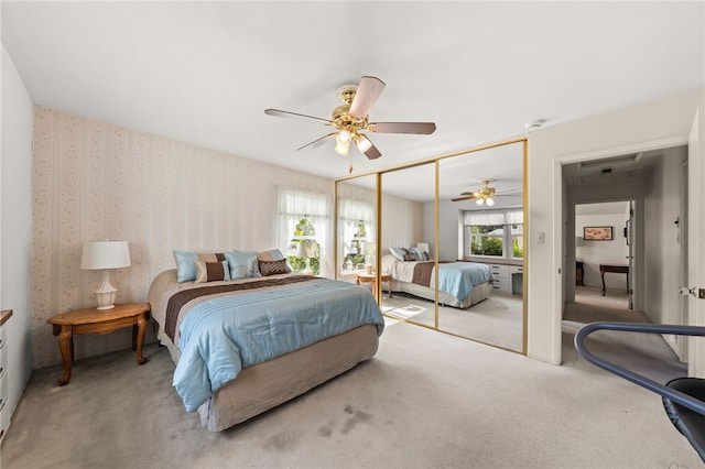 carpeted bedroom with a closet, ceiling fan, and wallpapered walls