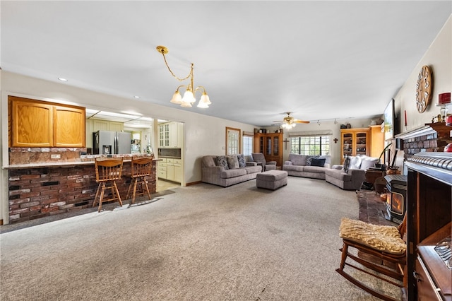 living room with carpet floors, recessed lighting, a wood stove, and ceiling fan with notable chandelier