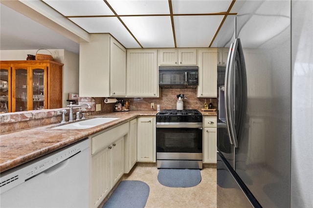 kitchen featuring stainless steel appliances, cream cabinetry, backsplash, and a sink