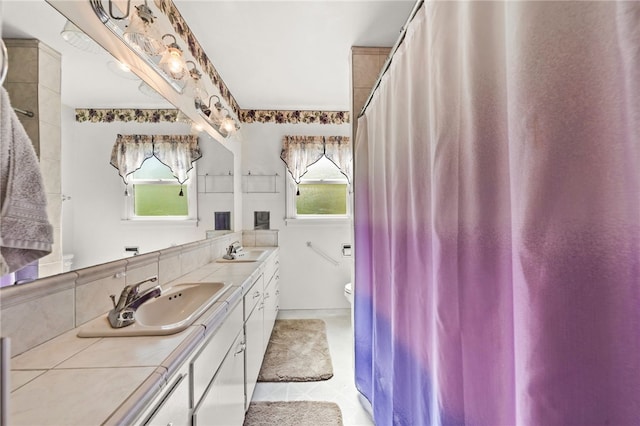 full bath with a wealth of natural light, a sink, and double vanity