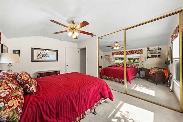 bedroom with a ceiling fan, lofted ceiling, a closet, and light carpet