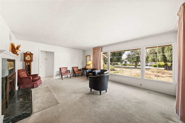 sitting room featuring carpet floors, ornamental molding, and a tiled fireplace