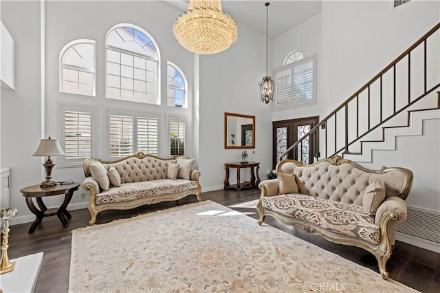 living room with dark wood finished floors, a notable chandelier, baseboards, and stairs