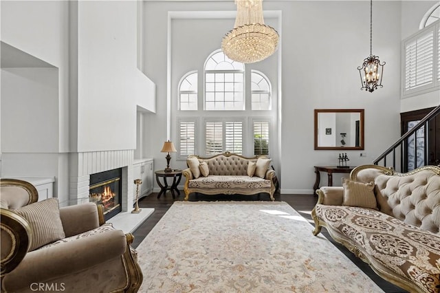 living room featuring dark wood-style flooring, a healthy amount of sunlight, a notable chandelier, and a towering ceiling