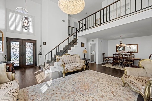 living area with plenty of natural light, dark wood-style flooring, a notable chandelier, and stairs