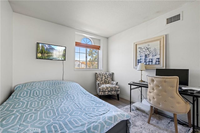 bedroom featuring wood finished floors, visible vents, and baseboards