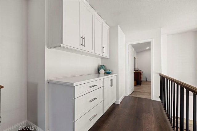 hall with dark wood-style floors and baseboards