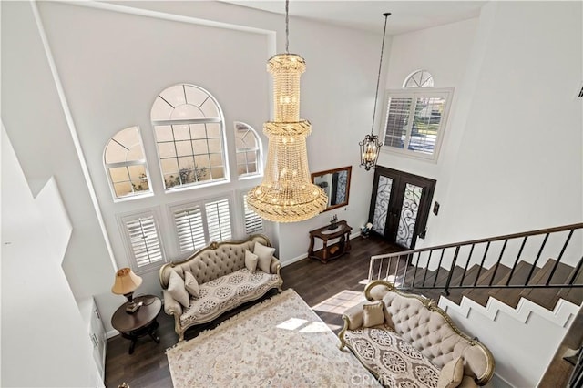 living area featuring stairway, plenty of natural light, a towering ceiling, and a notable chandelier