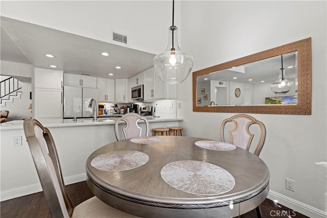 dining space featuring baseboards, visible vents, dark wood finished floors, stairway, and recessed lighting