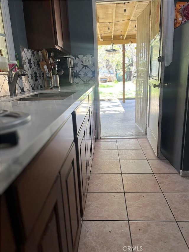 interior space with dark brown cabinetry, light tile patterned floors, light countertops, and a sink