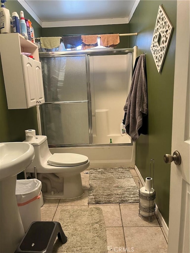 full bathroom with crown molding, toilet, combined bath / shower with glass door, tile patterned flooring, and baseboards