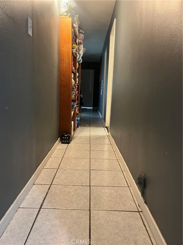 corridor with baseboards and light tile patterned floors