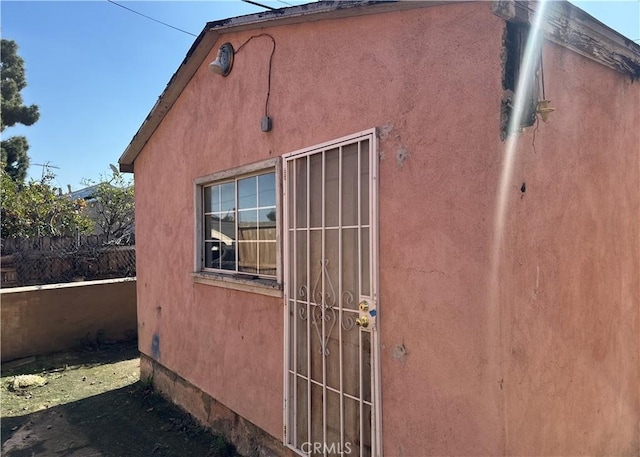 view of side of property featuring fence and stucco siding