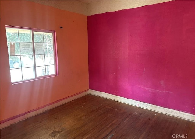 empty room featuring dark wood-type flooring and baseboards