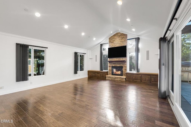 unfurnished living room with lofted ceiling, a stone fireplace, dark wood-type flooring, baseboards, and crown molding